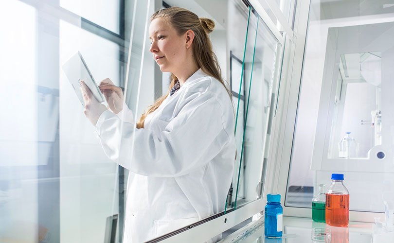 Travailleur de laboratoire avec un iPad devant une hotte aspirante
